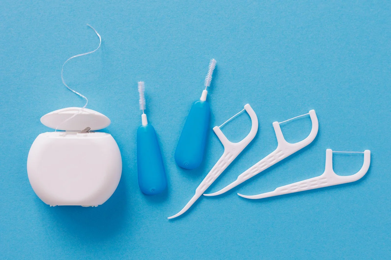 Dental floss, interdental brushes and floss picks on a blue background