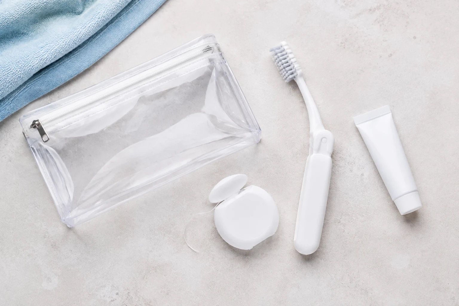 Travel toothbrush, dental floss, toothpaste, and a toiletry pouch ready to pack