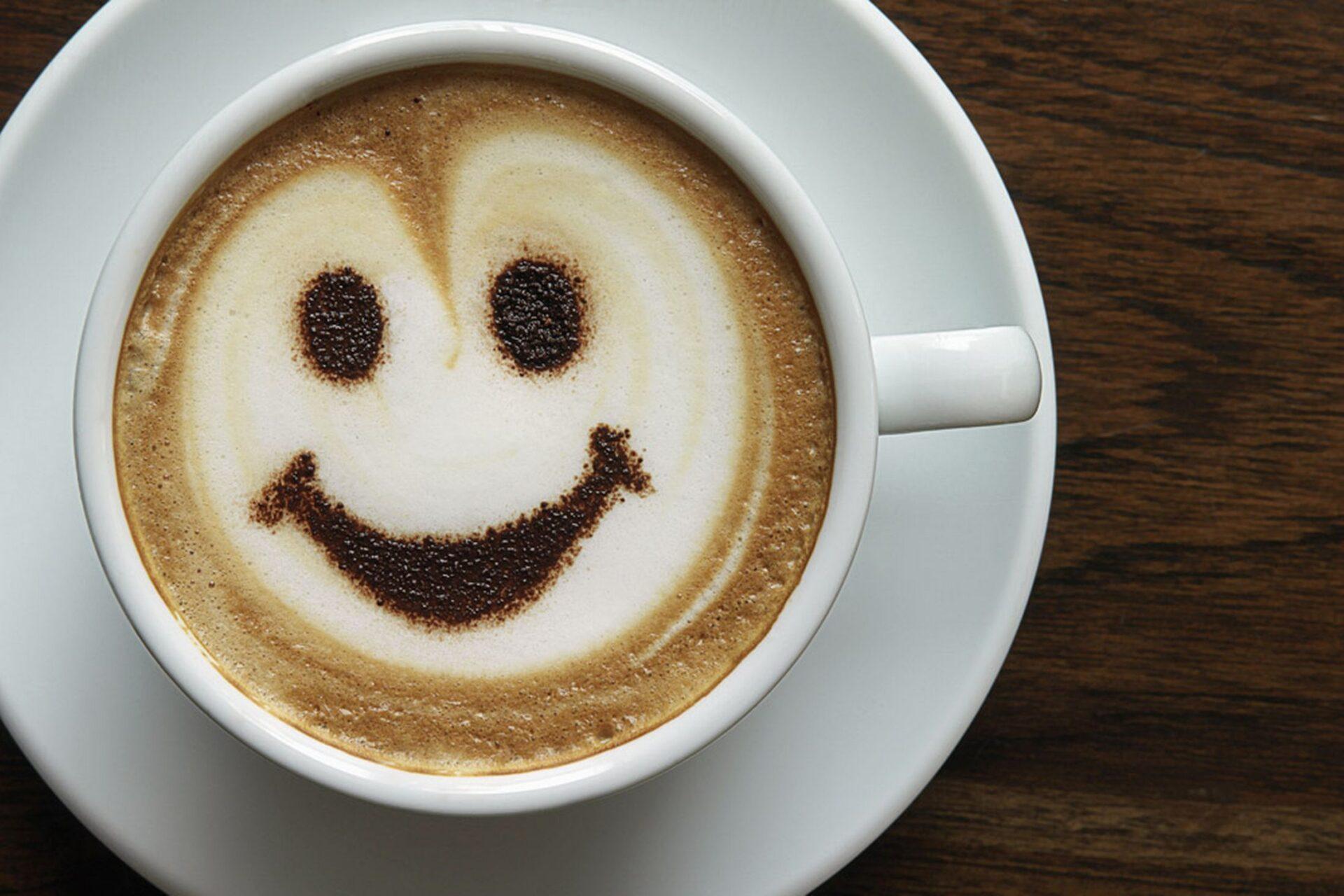 A cup of coffee beside a smiling face illustration